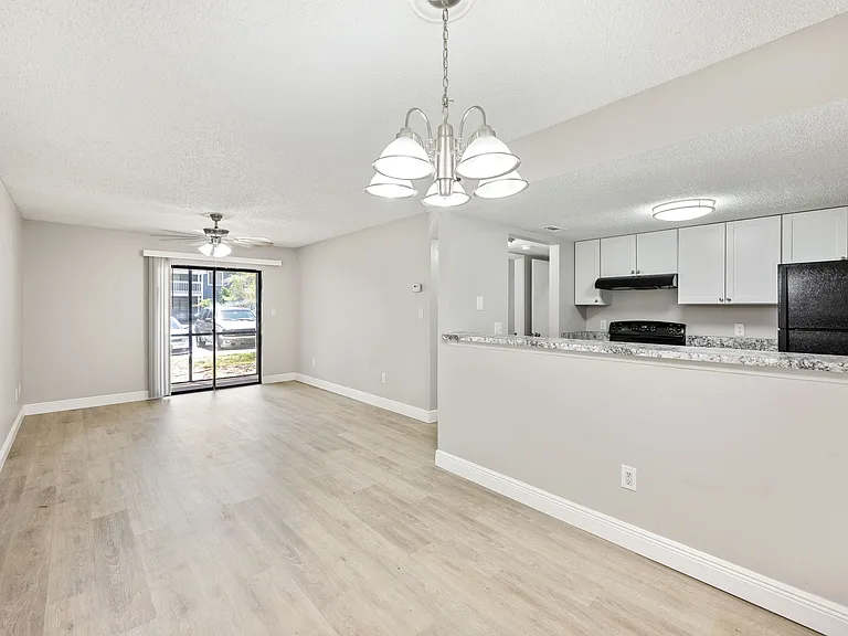 Inviting open-concept living area with elegant wood flooring, modern lighting, and a sleek kitchen perfect for entertaining.