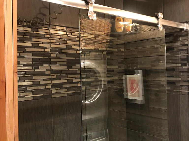 Large shower with rain showerhead. Shaving mirror on the wall.