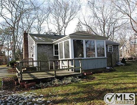 Back angle of house with deck, sunroom & outside shower.