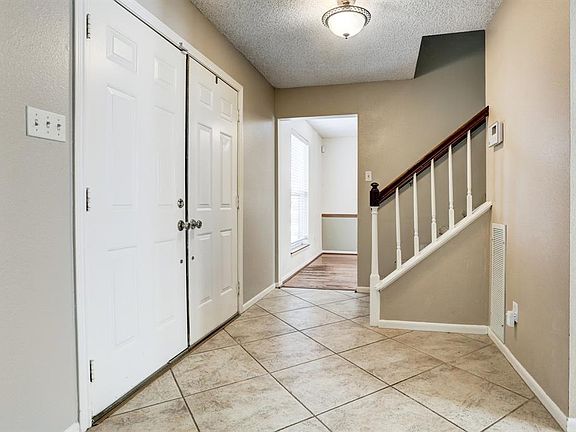 Entry/Foyer. 19.5"-square stone-like Italian porcelain tile floor, laid on a diagonal. Double metal front doors; neutral tone wall color, white ceiling & trim, newer light fixture. Staircase with wood rail & white balusters. Openings to Dining Room (