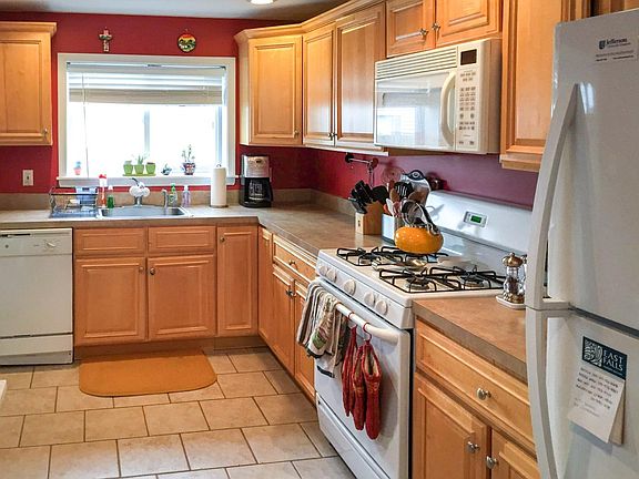 Kitchen area, complete with gas range, microwave, dishwasher, and refrigerator. Not pictured - access to basement (by the refrigerator), access to the back patio (to the left of the dishwasher), and additional space in the kitchen for a small table.