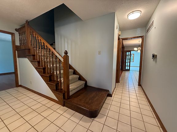 Foyer showing family room to the left, staircase to second floor, and hallway with half bathroom