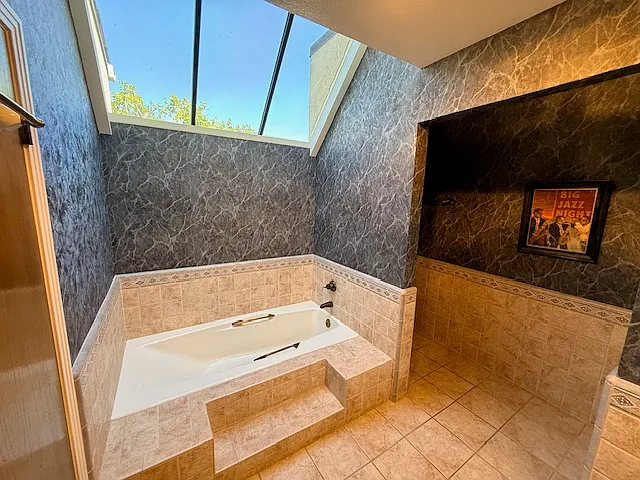 Primary bathroom tub with large skylight