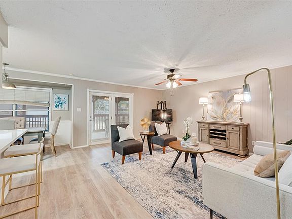 Living room with ornamental molding, a textured ceiling, ceiling fan, and light hardwood / wood-style floors