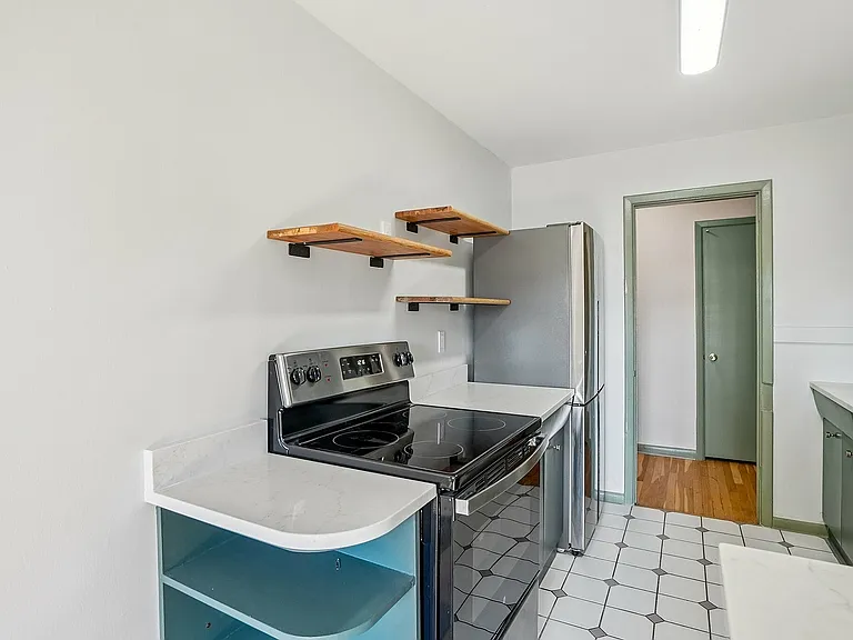 Modern kitchen with sleek stainless steel appliances, stylish open wooden shelves, and elegant tile flooring.