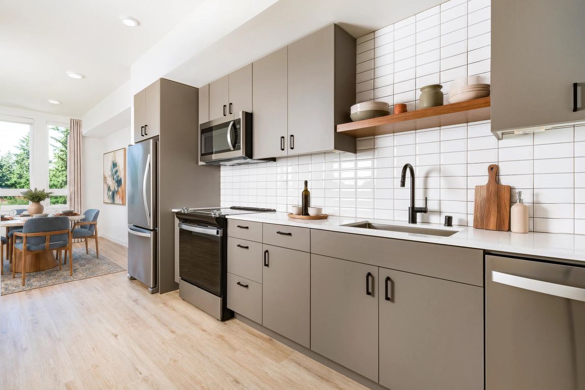 Designer kitchens feature flat-panel cabinetry, stainless steel appliances, quartz-style countertops, and a full-height tile backsplash that delivers a clean, modern aesthetic.