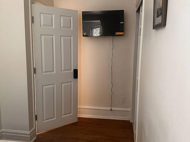 Bedroom space with hardwood flooring, wall-mounted TV, and easy access to an adjacent closet for convenient storage.