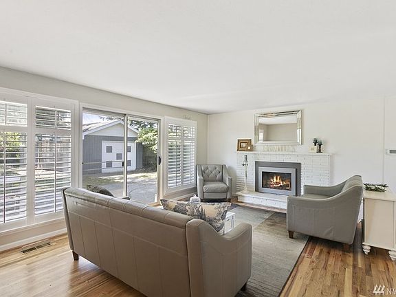 This gorgeous living room is sure to delight with a beautiful gas fireplace, gleaming hardwood floors, a wall of windows and slider to the huge backyard. Nearly all of the home's windows feature lovely plantation shutters.