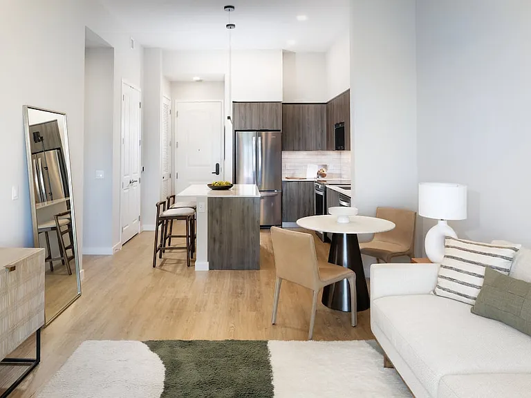 Living, dining, and kitchen space with espresso cabinetry, white tile backsplash, white quartz countertop, and hard-surface vinyl plank flooring