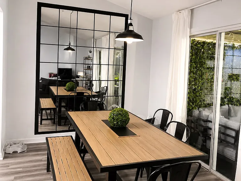 Modern dining area featuring a statement industrial-style mirror and dinning lamp.
