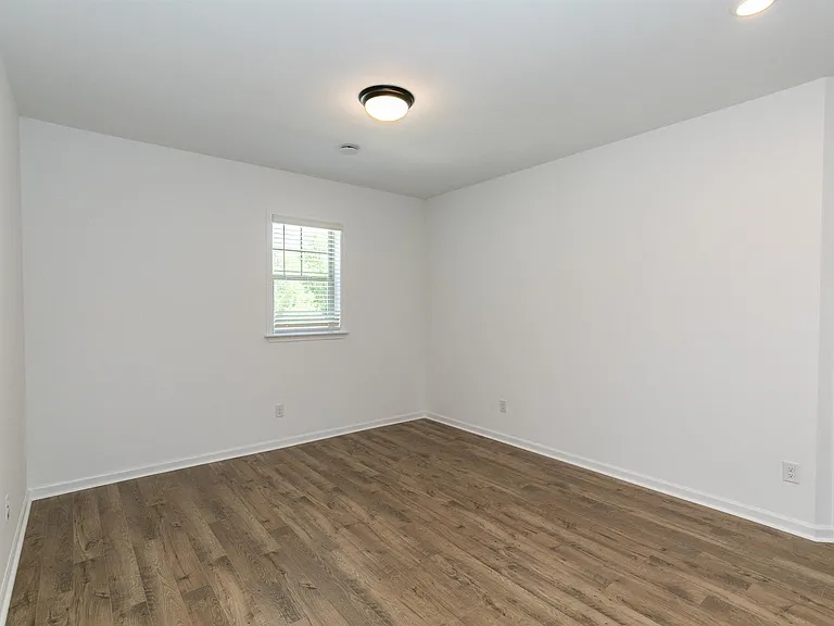 Bedroom with hardwood flooring and windows for natural lighting.