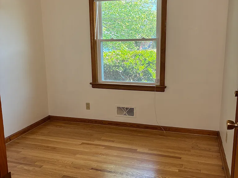 Comfortable bedroom with hardwood floors, a closet and a window.