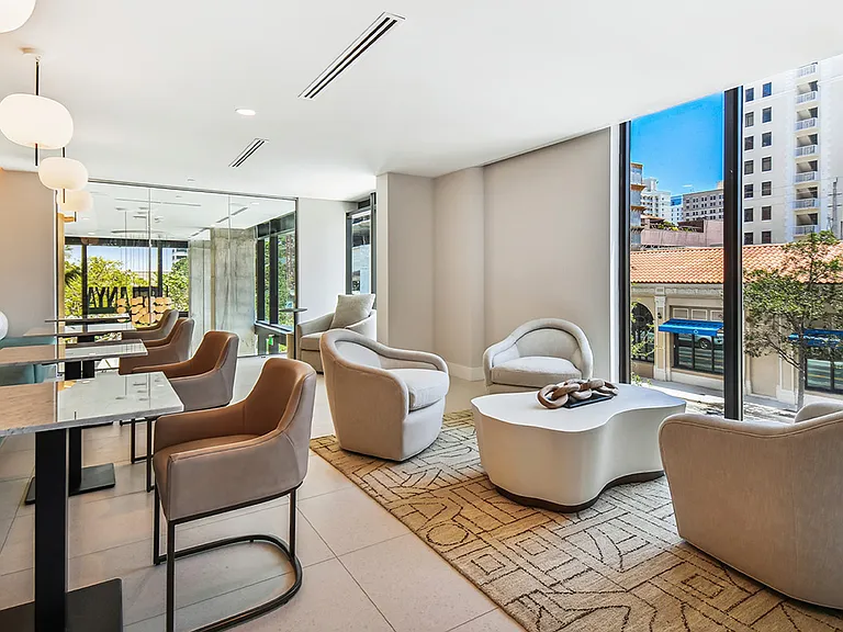 Griffis West Palm apartments coworking lounge with plush seating and floor to ceiling windows.