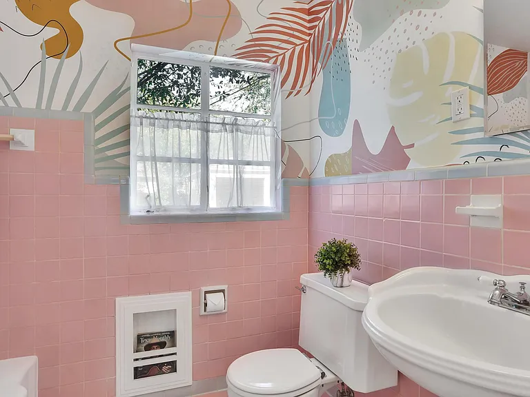 Bathroom with original bathroom tiles, built-in magazine rack, and fun wallpaper for a retro feel.