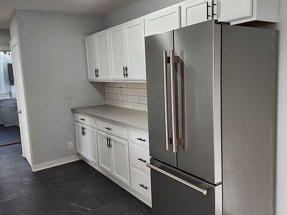 Other side of kitchen with stainless steel fridge with ice maker.