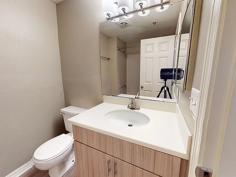 Apartment bathroom with wood-style flooring.