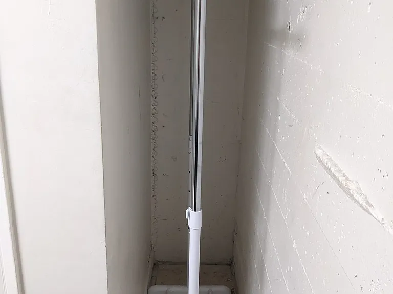 storage for brooms etc has portable rack to hang clothes
