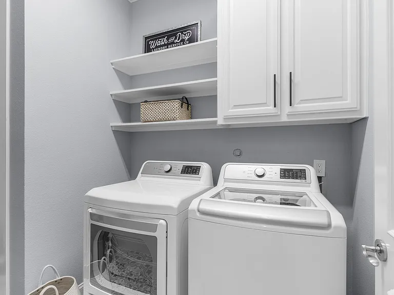 Primary laundry room with full-size appliances and ample storage.