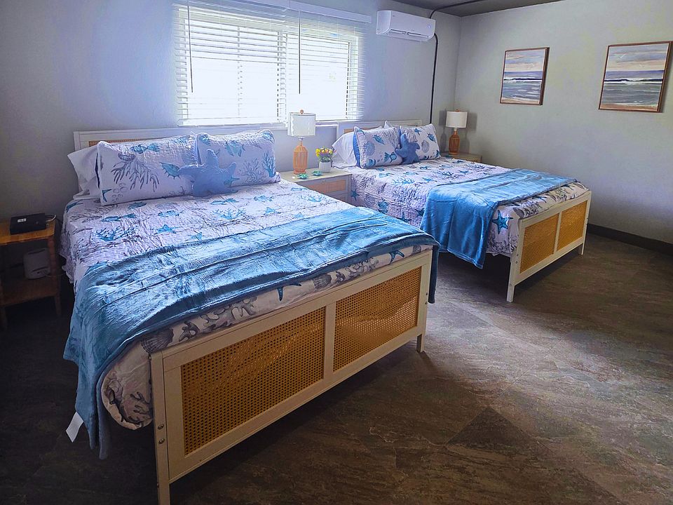 Spacious comfort room with 2 queen beds and bedside lamps