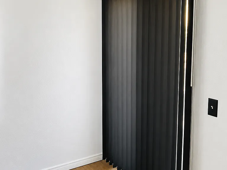 Modern matte black blinds in the primary bedroom with direct access to the private balcony, adding a sleek contemporary touch while providing privacy and natural light control.