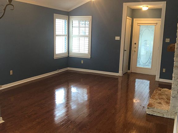 Beautiful living room with vaulted ceilings, hardwood floors, fireplace, and plantation shutters. This shows the etched glass front door.