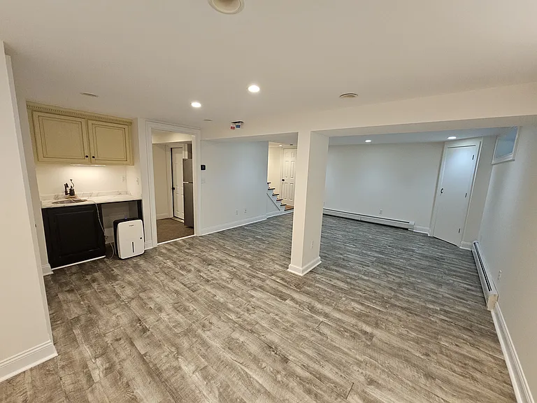 Basement Living Area _ View 2
Additional view showing the open living space and convenient kitchenette area with cabinets, countertop and sink. Also a full size refrigerator and fridge on the hallway