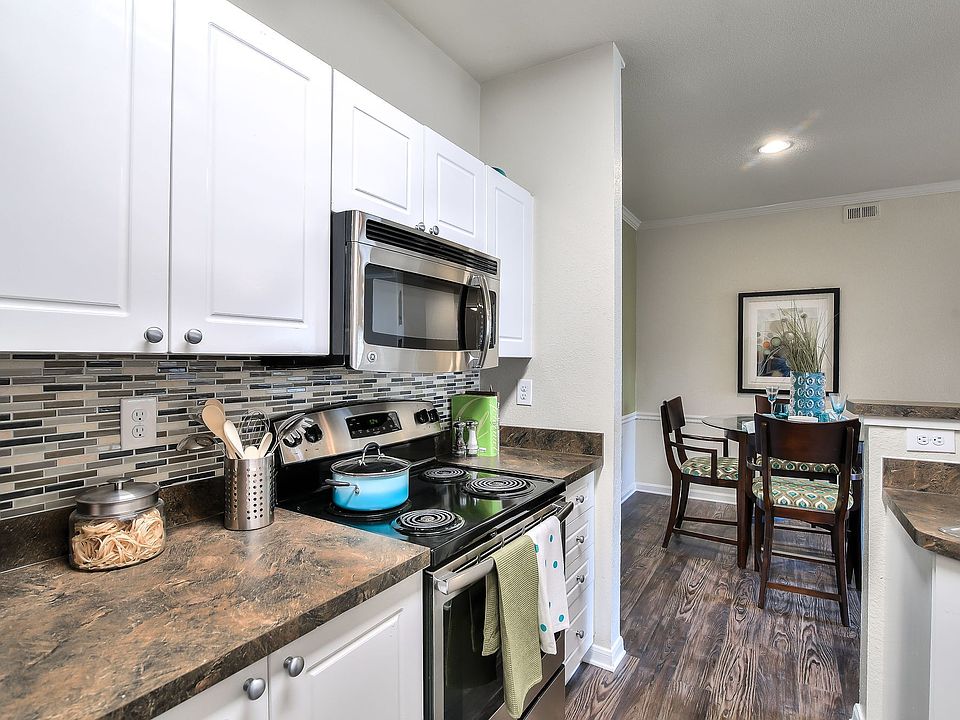 Kitchen featuring stainless front appliances, large Formica counter tops, and white cabinets.