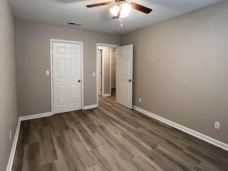 Another view of the third bedroom showing its closet and the same cohesive wood-look flooring found throughout the home.