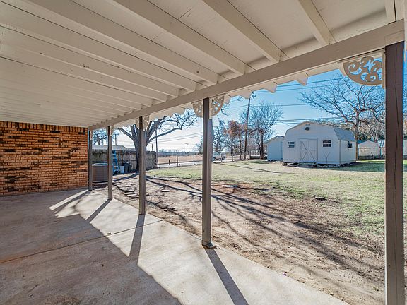 Large covered patio overlooking fenced yard and workshop building