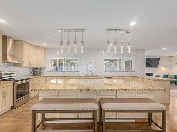 Stunning open concept kitchen that features new stainless steel appliances, huge 7.5 foot granite island with pendant lighting, never ending cabinets and a large farm sink.