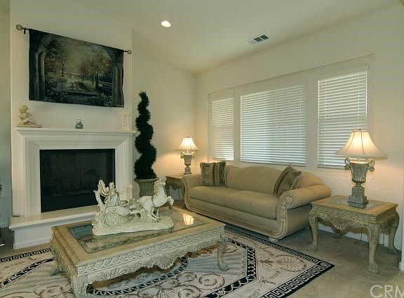 Formal living room with Hunter Douglas window coverings, recessed lighting and fireplace with raised