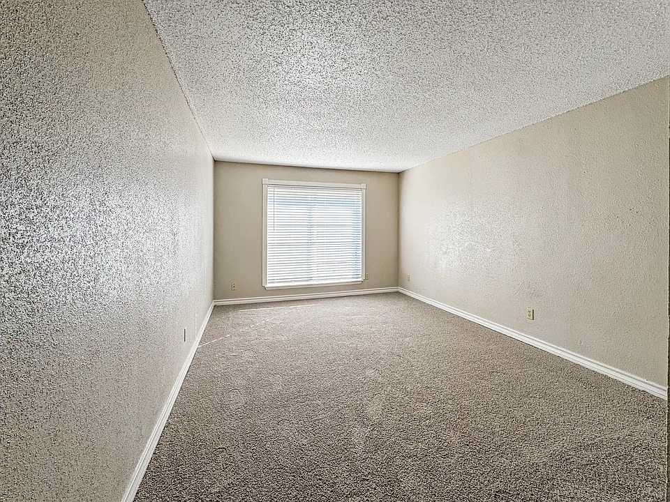 Comfortable bedroom with plush carpet and plenty of natural light at Borders Apartments, Brownsville TX.