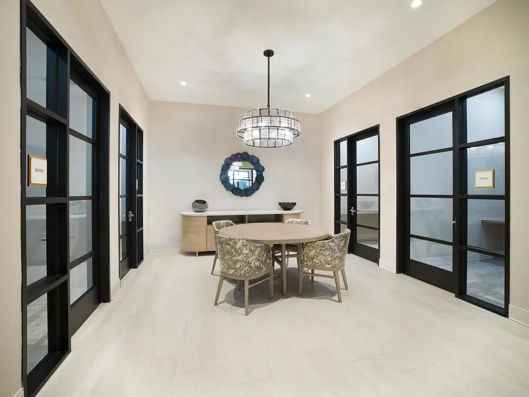 A private meeting room with a round table and glass-front offices, offering a polished setting for focused work or small group collaboration.
