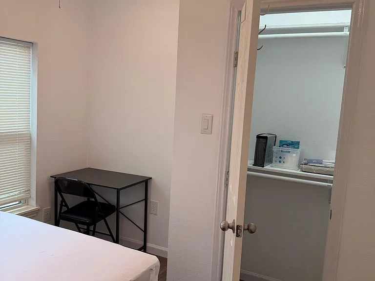 Bedroom with ceiling fan, window with blinds, and a compact desk; includes nearby walk-in closet for convenient storage.
