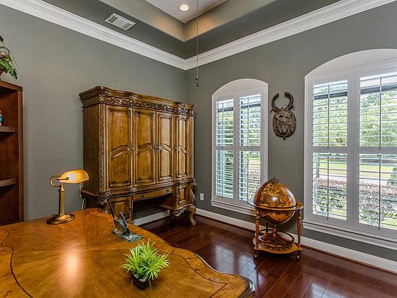 Private Study with tray ceilings and hardwood floors that overlook the greenbelt in front of the home.