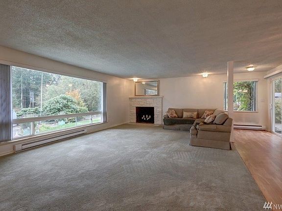 Large living room with wood burning fireplace and sliding door opening onto patio off dining area.