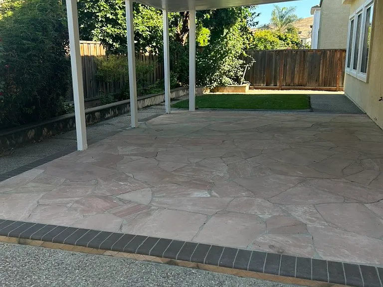 Backyard with covered sitting area, small lawn area, with plenty of fruit, flower, and vegetable trees, freshly painted roof and exteriors