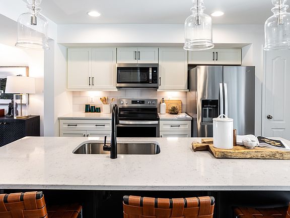 Beautiful open kitchen with white cabinets, white counters, large island with sink and pendant light
