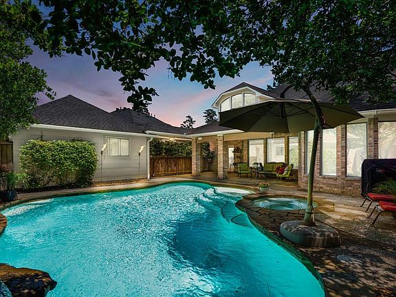 Out in the backyard is a large covered patio, sparkling pool, spa & waterfall. The large umbrella & pool items convey.