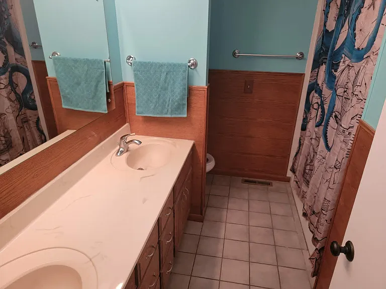 Full bathroom includes tub/shower, toilet, two sinks and linen storage.