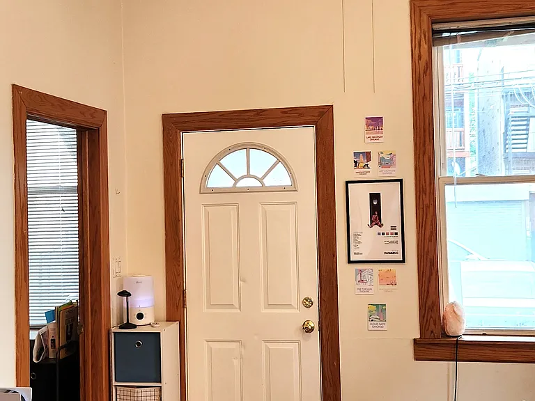Living room with closed back door and open entrance to smaller bedroom/office.