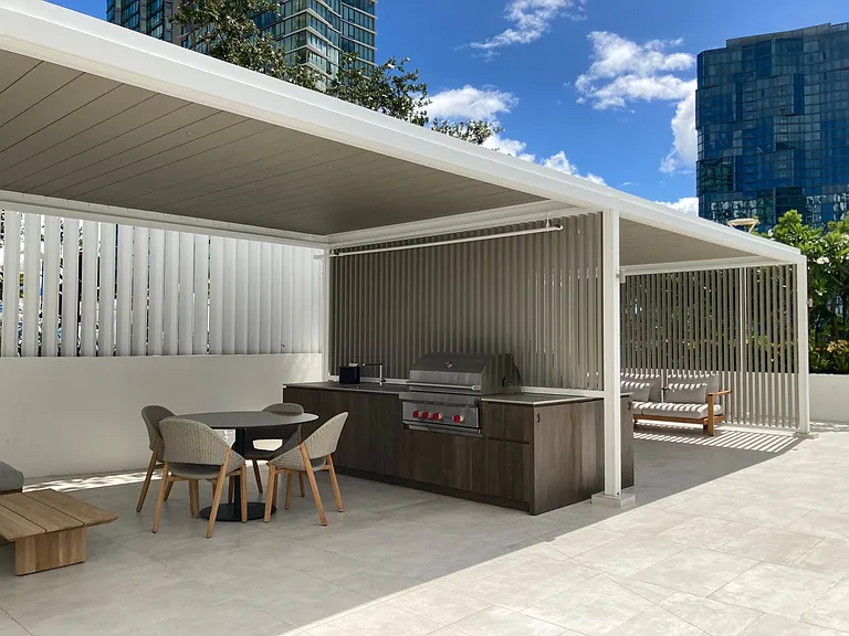 Multiple bbq cabanas next to pool.