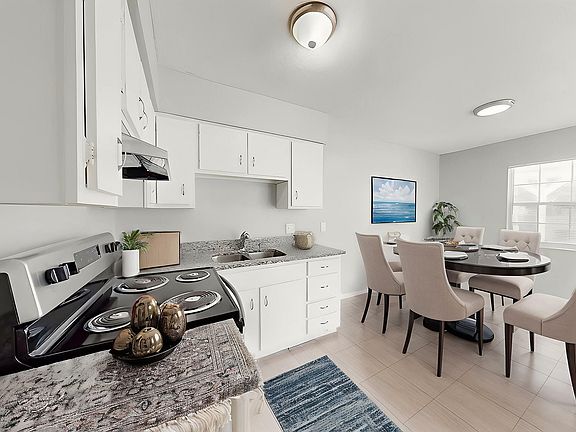 Modern kitchen and dining area featuring sleek appliances, elegant dining table, and ample natural light.