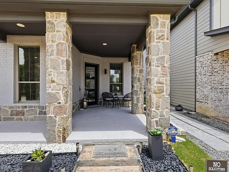 Covered front porch with stone columns and recessed lighting.