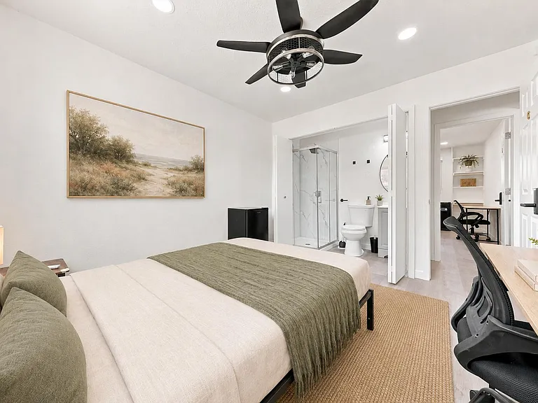 Well-appointed bedroom with a ceiling fan, dedicated desk area, and direct access to a private ensuite bath.