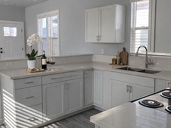 Modern kitchen featuring white shaker cabinetry, quartz countertops, stainless steel appliances, ample storage, and a practical layout designed for everyday living.