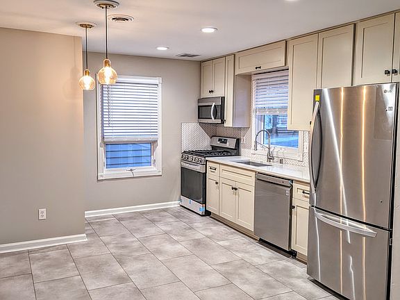 Beautifully Updated Kitchen - New floors, sleek White cabinetry, Quartz countertops, Stainless Steel appliances, and Herringbone backsplash.