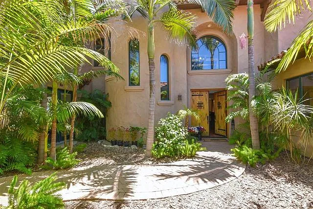 Front entry with custom built double doors and lush landscaping