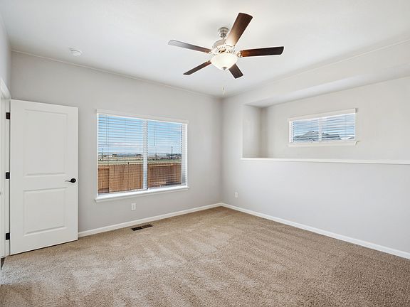 Spacious master bedroom with a ceiling fan and windows.