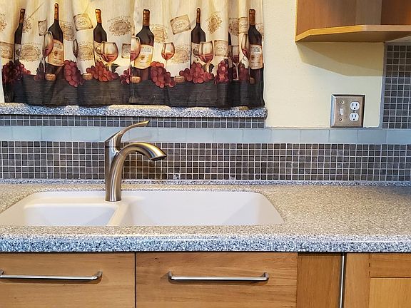 Corian countertops wrap around the kitchen and cover the island. Limestone backsplash.